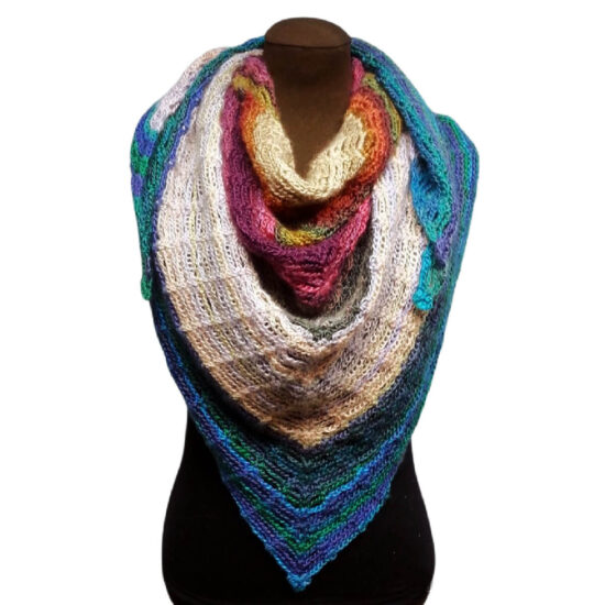 Front of a brown dress form in a black tank top with a triangular crochet shawl with stripes of varying sizes in shades of cream, pink, green, and blue. The shawl point is in the front and the sides are gathered up and wrapped around the neck.
