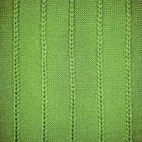 Flat view of a square section of knit. The yarn is grass green and knit in the garter stitch with 5 vertical sections of chunky chains made with several strands of yarn in each chain.
