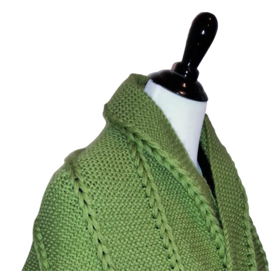 Close up of the side of the top of a dress form with a shawl wrapped around the shoulders. The yarn is grass green and knit in the garter stitch with 5 vertical sections of chunky chains made with several strands of yarn in each chain.