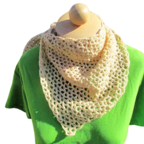 Top half of a dress form in a green tee shirt and a stretched asymmetrical triangular v-stitch crochet wrap with a long, skinny end, wrap is crocheted with cream yarn. The long side of the shawl is wrapped around the neck so the side opposite the skinny point is draped in front and the rest wraps around.