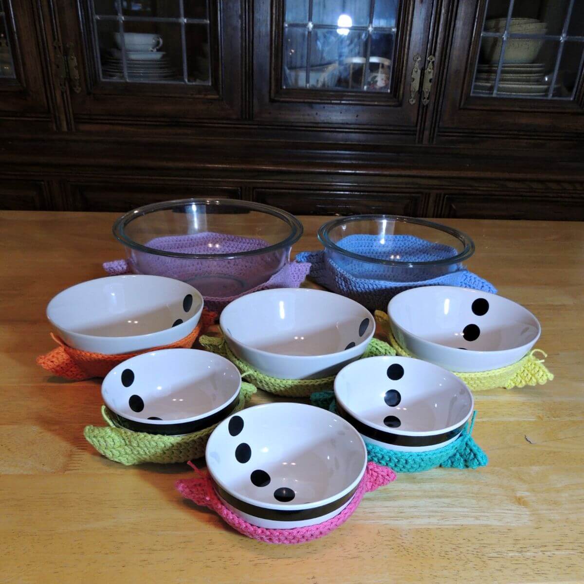 Image of several bowls in crochet bowl cozies of various colors.