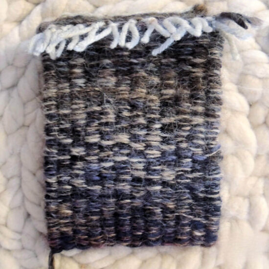 A small woven pouch in navy blue with bits of brown and cream.