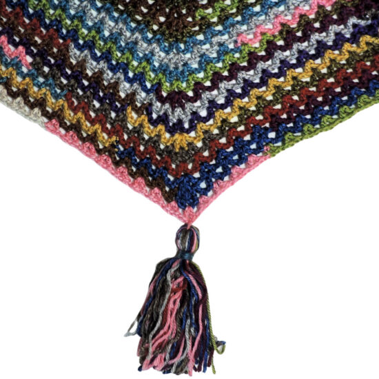 Close up multicolor V-stitch crochet that comes to a point. Hanging from the point is a large tassel.