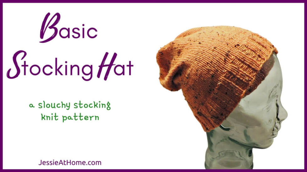 White horizontal rectangle with purple boarder. On the left is text "Basic Stocking Hat", "a slouchy stocking hat knit pattern" and "Jessie At Home dot com." On the right is a photo of the side of glass mannequin head in an orange tweed knit stocking hat with rib stitches at bottom and stockinette stitches for rest of hat. Top is gathered to close.