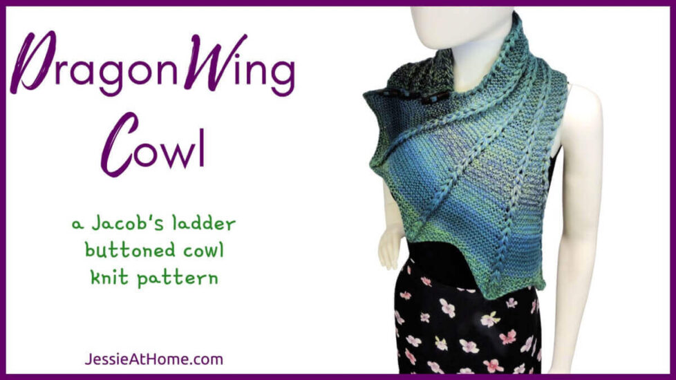 White horizontal rectangle with purple boarder. On the left is text "Dragon Wing Cowl", "a Jacob's ladder buttoned cowl knit pattern" and "Jessie At Home dot com." On the right is an image of a white mannequin in black tank top and blue and green variegated knit cowl that's thin on one end then wraps around the neck and buttons to the other end which has flared out with 5 points. There are columns of raised large stitches from the short end to the tips.