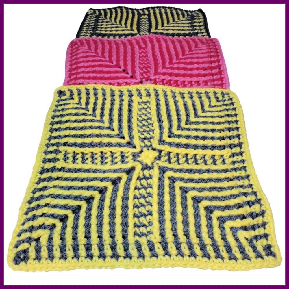 Three crochet squares, each covering the bottom half of the one before. All have angled stripes pointing in from corners made with post stitches. The first and last are gray and yellow and the middle is two tone pink.