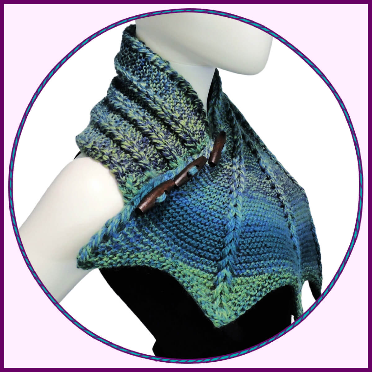 Round photo in pink square with purple border. Photo is side view of the top half of a white mannequin wearing a black tank top and a blue and green variegated knit buttoned cowl that is thin on one end then wraps around the neck and buttons to the other end which has flared out with 5 points. There are columns of raised large stitches from the short end to the tips. The cowl is buttoned on the side facing us.