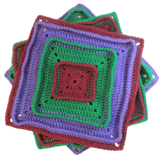 Three crochet squares stacked, each turned a bit so you can see the corners of the square below. Top square starts with burgundy on the inside, then has a section of green, then purple, then burgundy, each attached below the last round of the section before, making the last round stand up. Other 2 squares are the same with the colors in a different order.