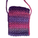 Close up of a small rectangular crochet bag in dark pink and purple color changing yarn.