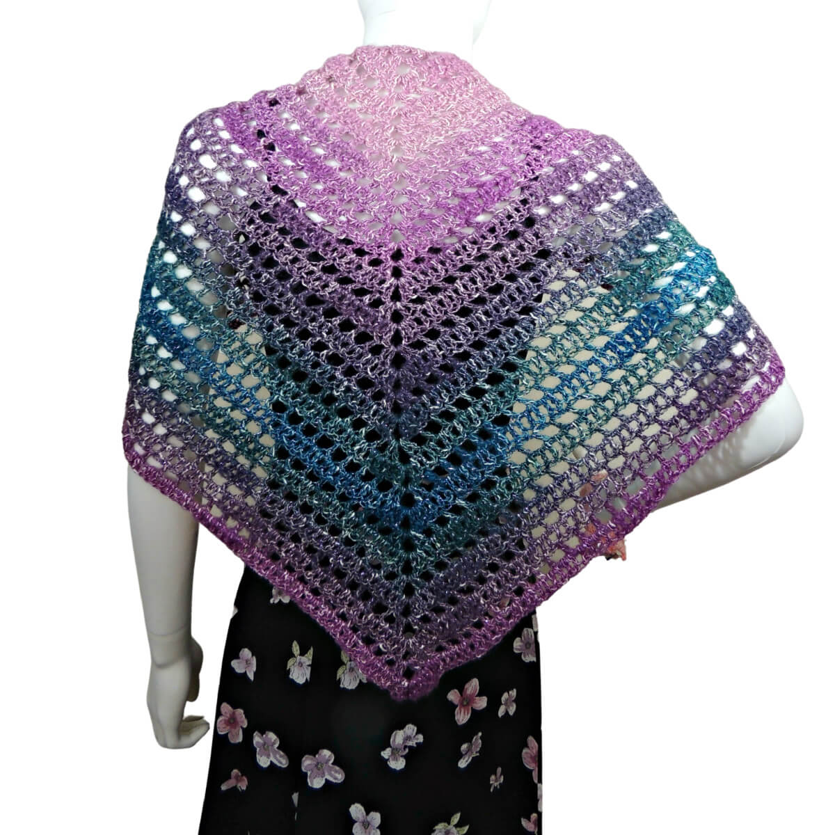 Back of a white mannequin in a black tank top, black skirt, and a triangular crochet shawl that changes colors through pink, purple, green, and blue. Shawl alternates between rows of solid stitches and rows of net or eyehole stitches. The shawl is laying flat across the back so the stitching can clearly be seen.
