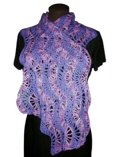 Waist up image of a brown dress form in a black dress with a rectangle wrap around it. The wrap is made of a crochet feather and fan stitch in stripes of medium and dark purple.