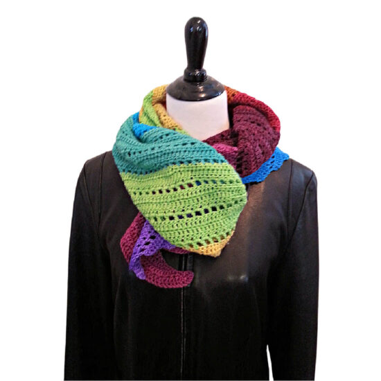 Front view of a dress form torso in a black leather coat. Wrapped and tucked around its neck like a scarf is a long crochet wrap or shawl in rainbow colors starting with purple and ending with blue.